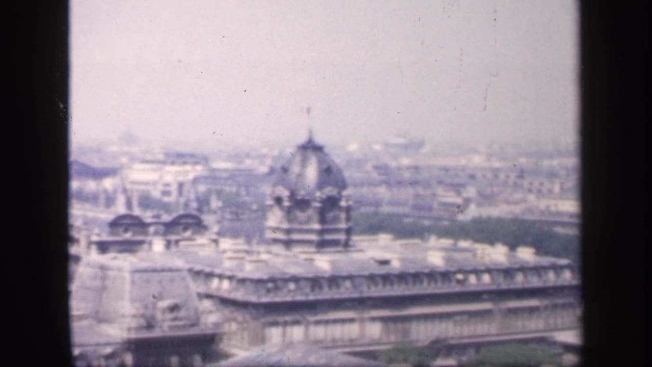 City panorama with ornate rooftop dome, broad street, and distant Paris buildings.