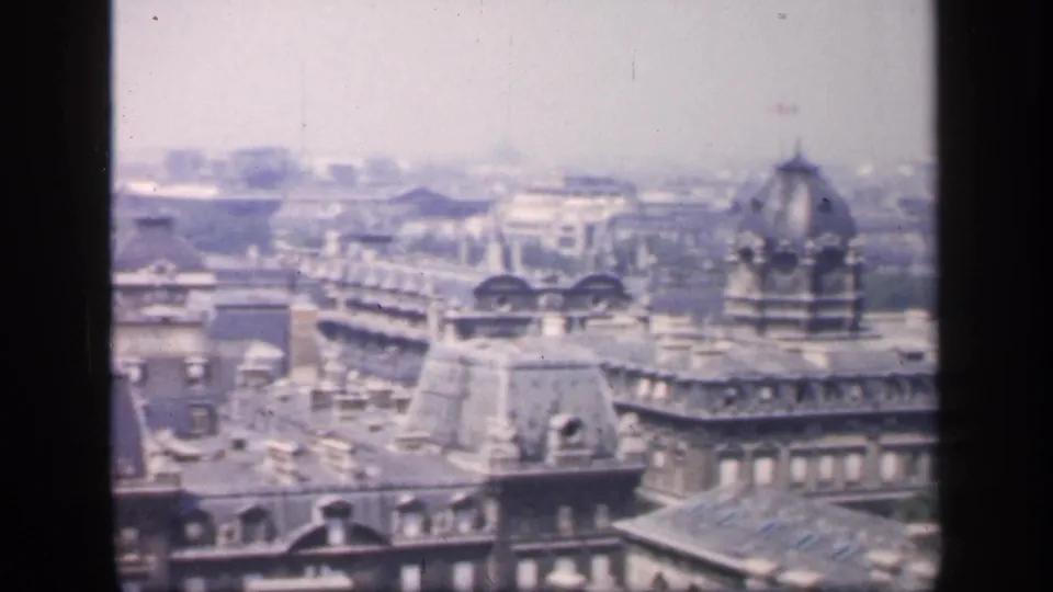 1949 France frame showing dense Paris rooftops, dormer windows, and a domed architectural element during a handheld pan.
