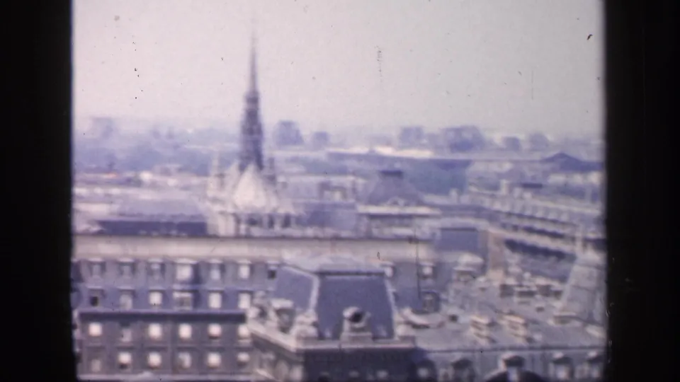 Final 1949 France frame from the pan, showing Paris rooftops and a distant spire-like form in a hazy skyline.