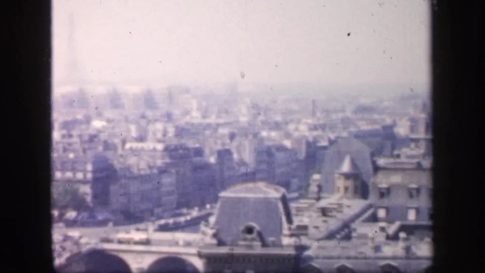 1949 France frame showing a wider hazy city panorama with foreground rooftops and dense urban blocks beyond.