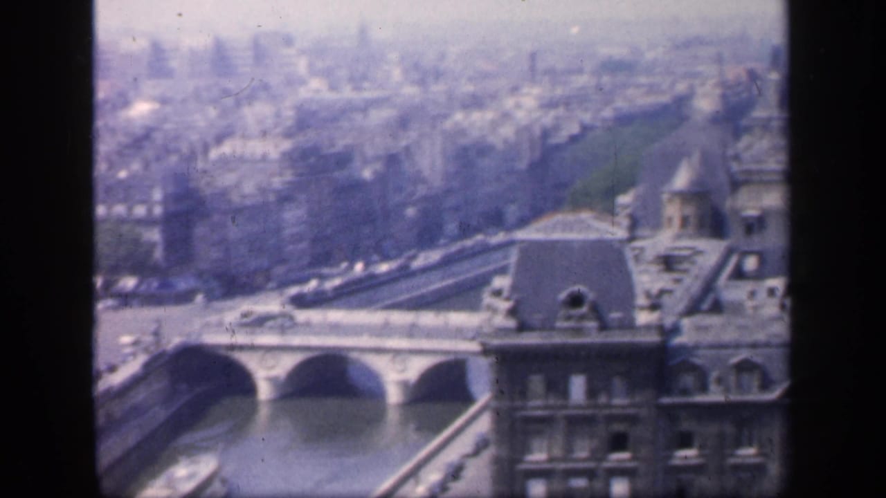Elevated 1949 Paris view with the Seine, arched bridge spans, rooftops, and distant city blocks visible in faded 8mm color.