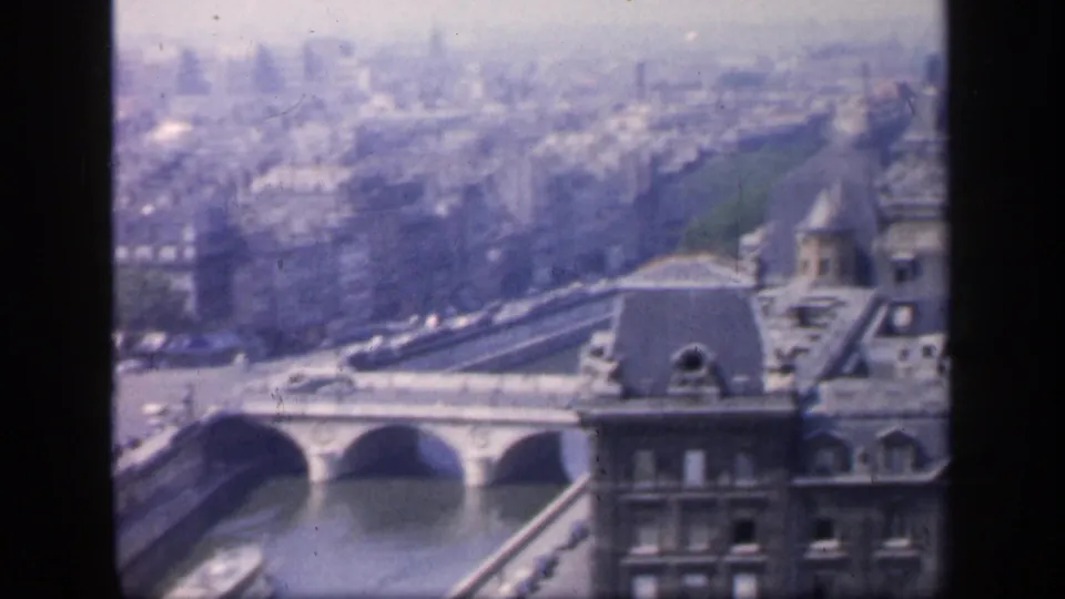 Elevated 1949 Paris view with the Seine, arched bridge spans, rooftops, and distant city blocks visible in faded 8mm color.