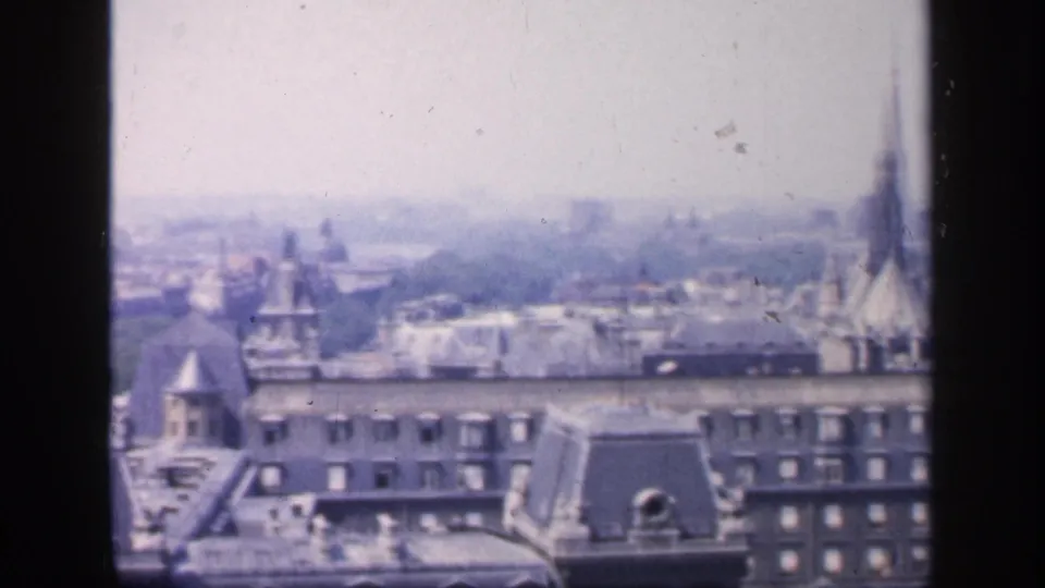 Hazy 1949 Paris skyline with mansard rooftops in the foreground and the Eiffel Tower faintly visible near the right side.