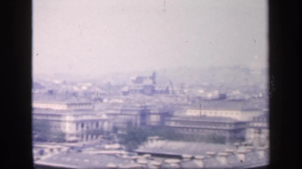 1949 New York City skyline view from above, with large masonry buildings and distant rooftops softened by haze.