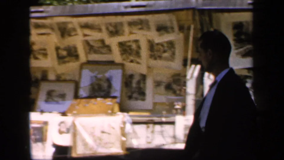 Profile view of a formally dressed figure beside a sunlit outdoor display of photographs in France, supported by 1949 clip metadata.