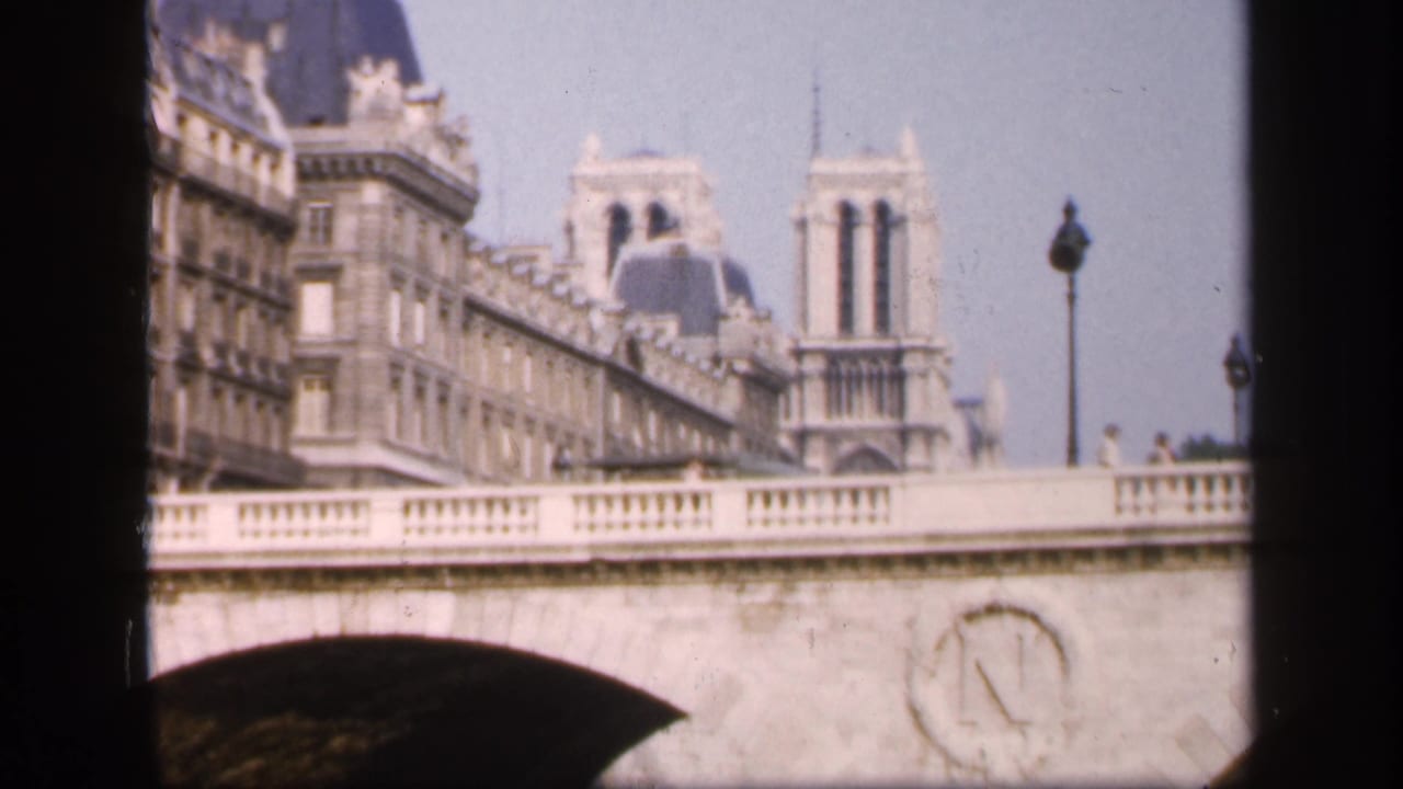 1949 8mm view of Notre-Dame Cathedral towers partly framed by a bridge and adjacent Paris buildings.