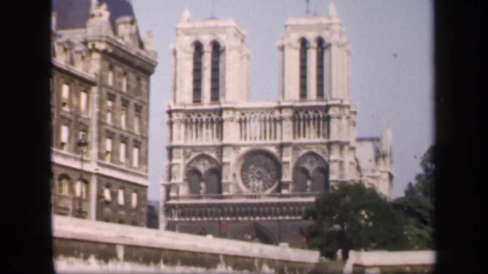1949 Paris 8mm view of Notre-Dame's twin towers and rose window, with trees and a bridge rail in the foreground.