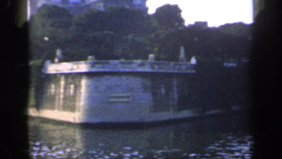 1949 France 8mm frame showing a wider waterside view with masonry, greenery, and reflective water under soft exposure.