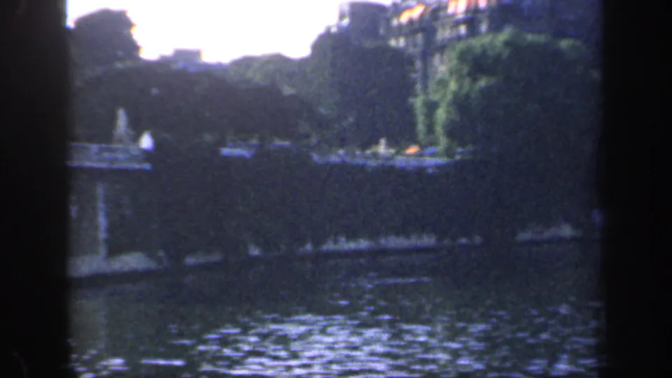 1949 France home-movie frame with rippling water, dense trees, ivy-covered masonry, and distant landmark details.