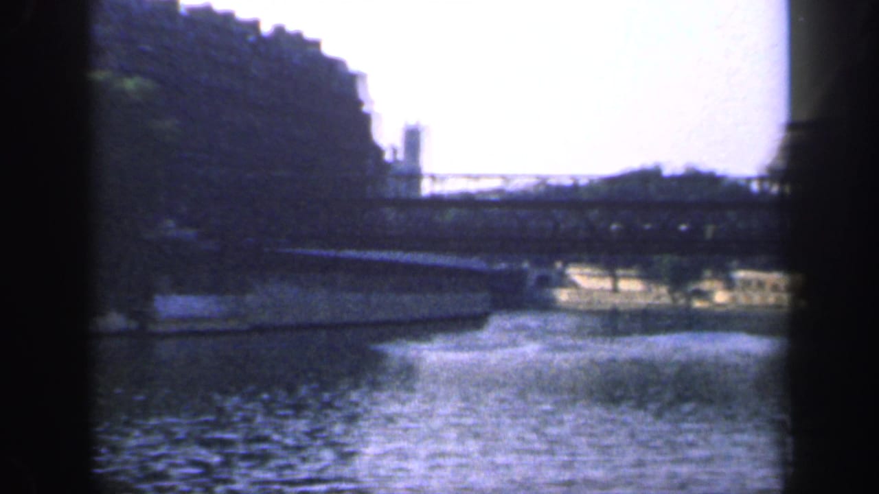 1949 France 8mm frame of a bridge over a river, with trees and stone riverbank visible behind dark contact-sheet borders.