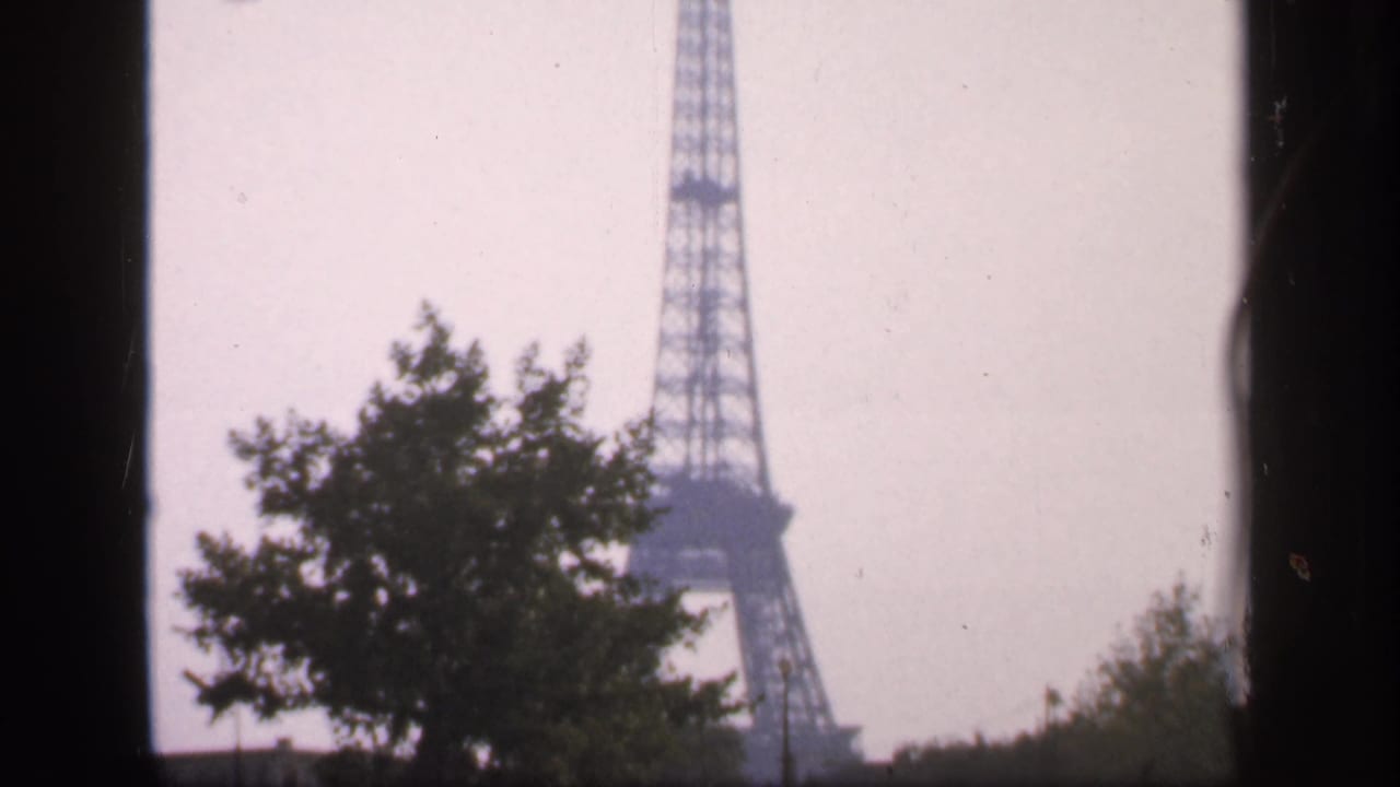 Eiffel Tower partly framed by trees and dark film edges.