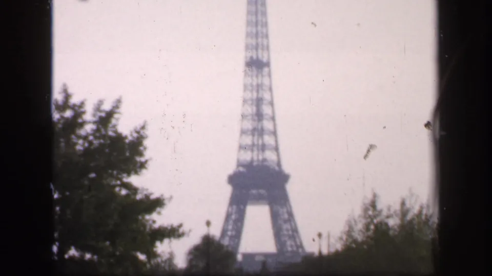A 1949 Paris frame shows the Eiffel Tower lower structure and base area partly screened by foliage.