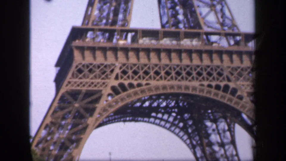 1949 Paris home-movie close-up of the Eiffel Tower's lower arch and latticework, framed by dark film edges.