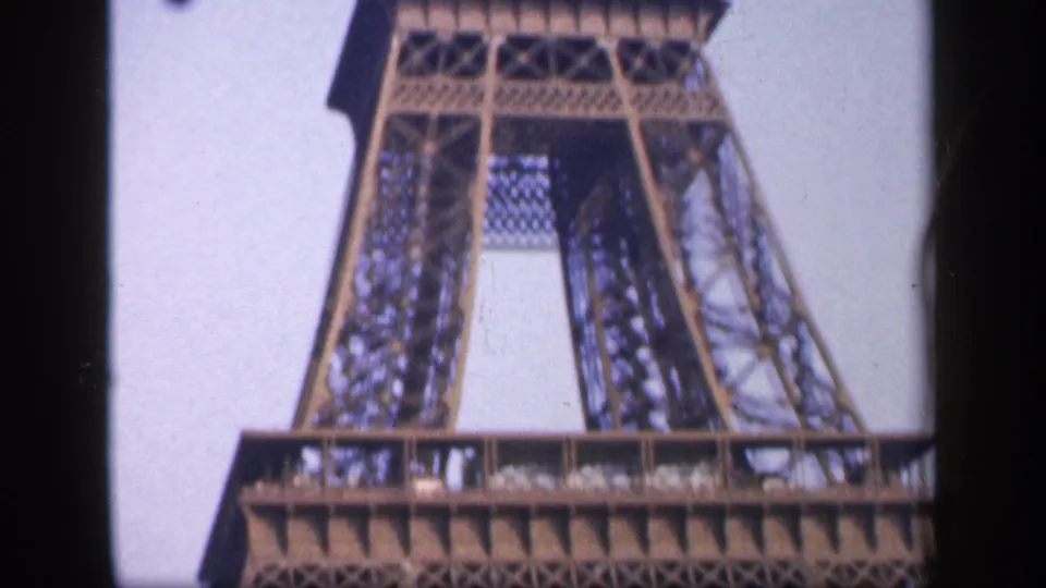 1949 Paris view looking up at the Eiffel Tower legs and platform, with small distant visitors visible along the deck.