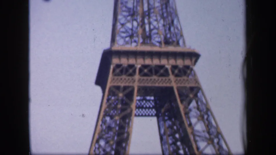 1949 8mm Paris view of the Eiffel Tower's upper structure and iron lattice seen from below against a bright sky.