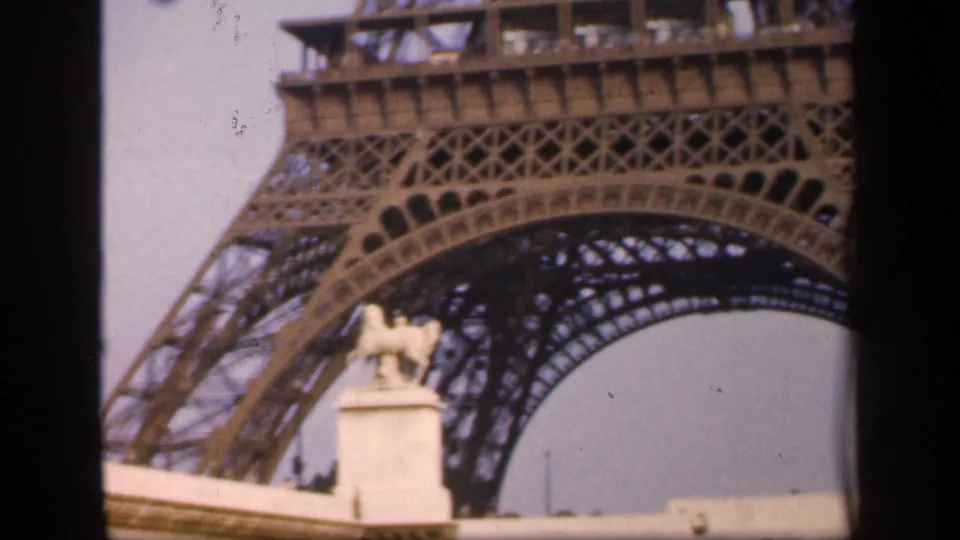 1949 Paris 8mm frame showing the Eiffel Tower base and arch, with a small foreground statue below the ironwork.