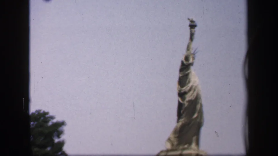1949 New York home-movie frame with the Statue of Liberty partly cropped at right, showing the torch, crown, robe, and pale sky.