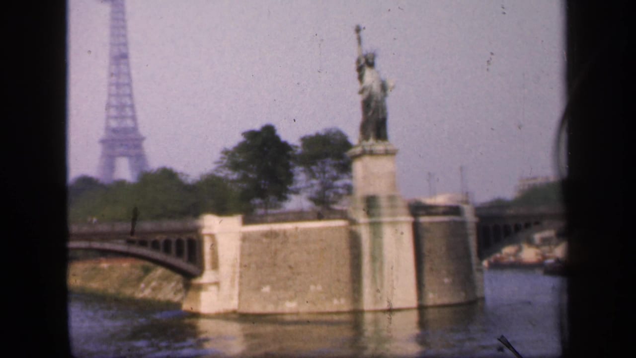 1949 Paris 8mm frame showing the Eiffel Tower in the distance and the Statue of Liberty replica on a riverside pier from the Seine.