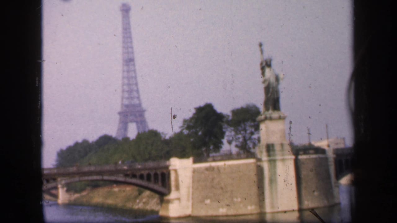 Riverbank bridge, Eiffel Tower, and Statue of Liberty replica viewed from a boat.