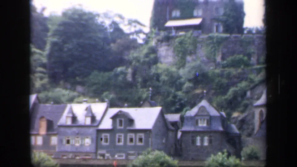 1949 Ireland frame showing several village buildings at the foot of a wooded hill with a stone landmark above.
