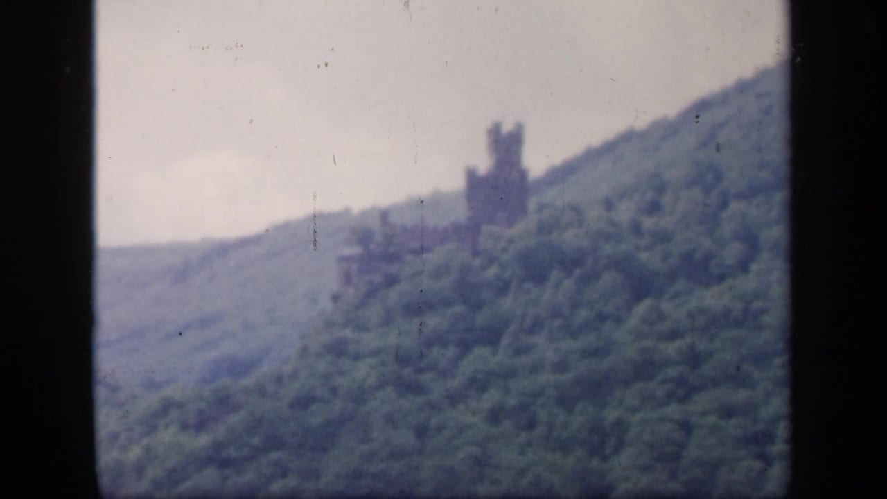 Wooded Irish hillside with a distant tower-like ruin near the ridge.