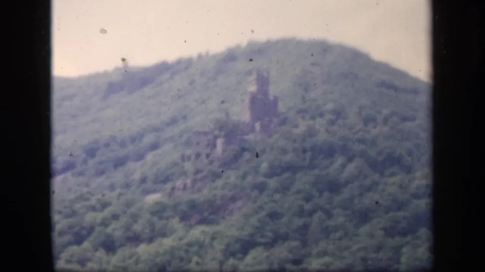 1949 Ireland 8mm frame with a soft view of the grey hillside ruin, green trees, and cloudy sky.