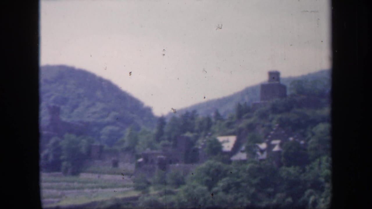 Wooded hills and a castle-like stone structure across a river valley.