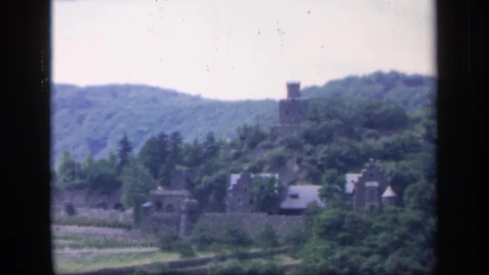 1949 Ireland 8mm frame showing a stone tower above trees, with rural buildings and fields below.