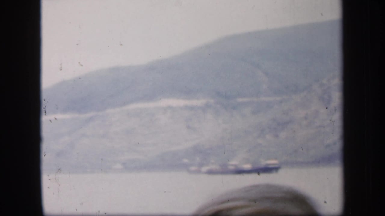 Distant water and hillside with dark window edges and a partial head at the bottom.