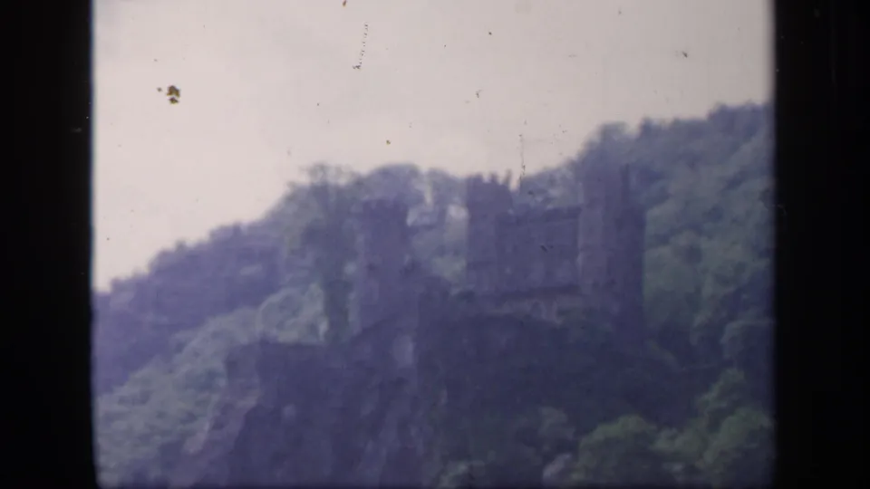 1949 Ireland 8mm frame showing a castle-like stone structure on a green hillside in soft focus.