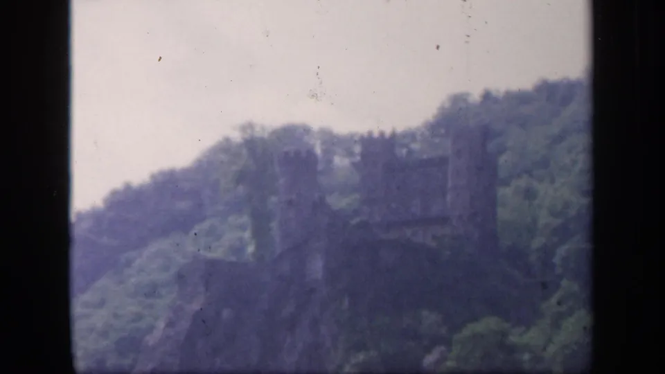 Soft 1949 Ireland home-movie frame of a stone castle-like landmark on a lush hillside.