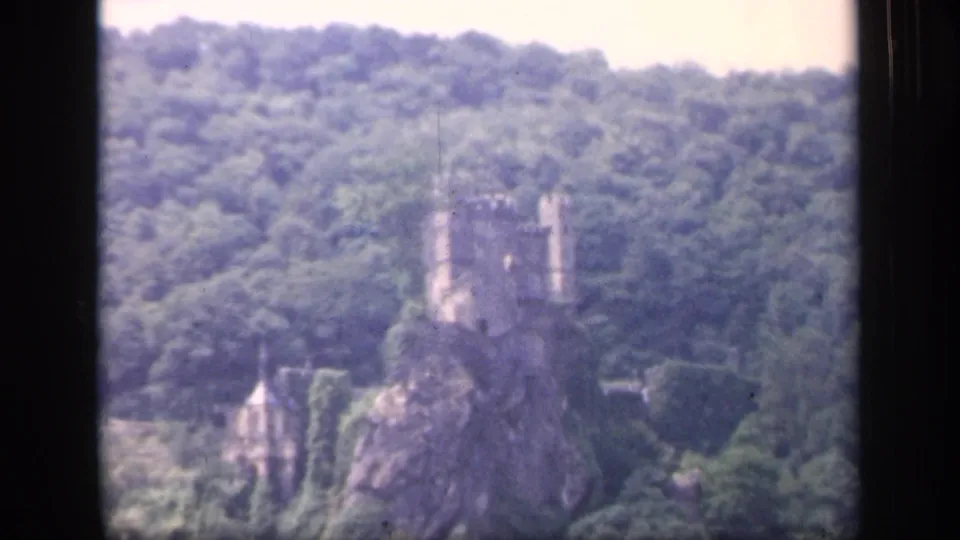 Distant 1949 Ireland view of a castle-like ruin above trees, framed by dark window or film edges.