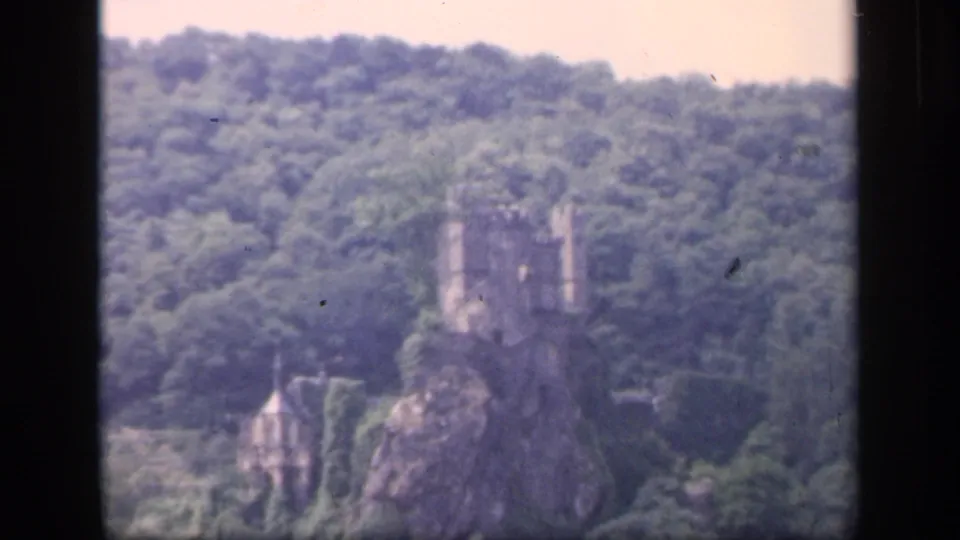 Soft 8mm frame from Ireland in 1949 showing a castle-like ruin on a rocky wooded hill with a smaller structure below.