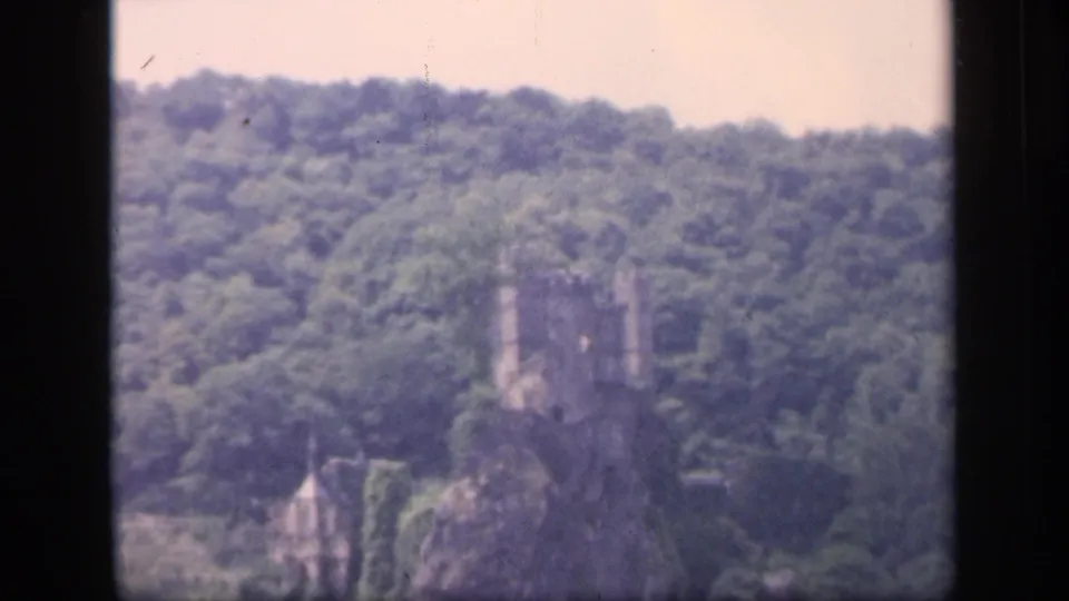 1949 Ireland home-movie frame showing an ivy-covered castle-like structure on a wooded rocky rise.