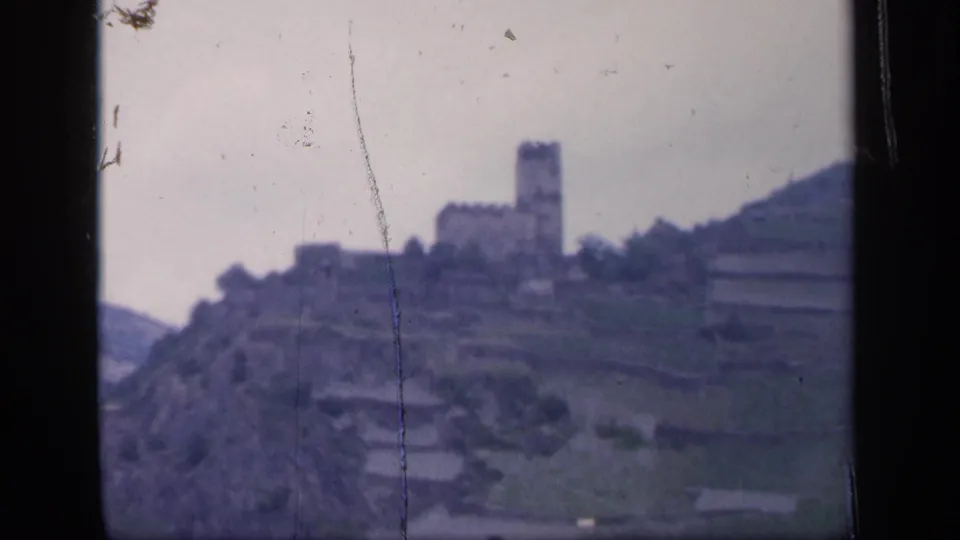 1949 Ireland home-movie view of a distant stone castle on a terraced hillside under a pale sky.