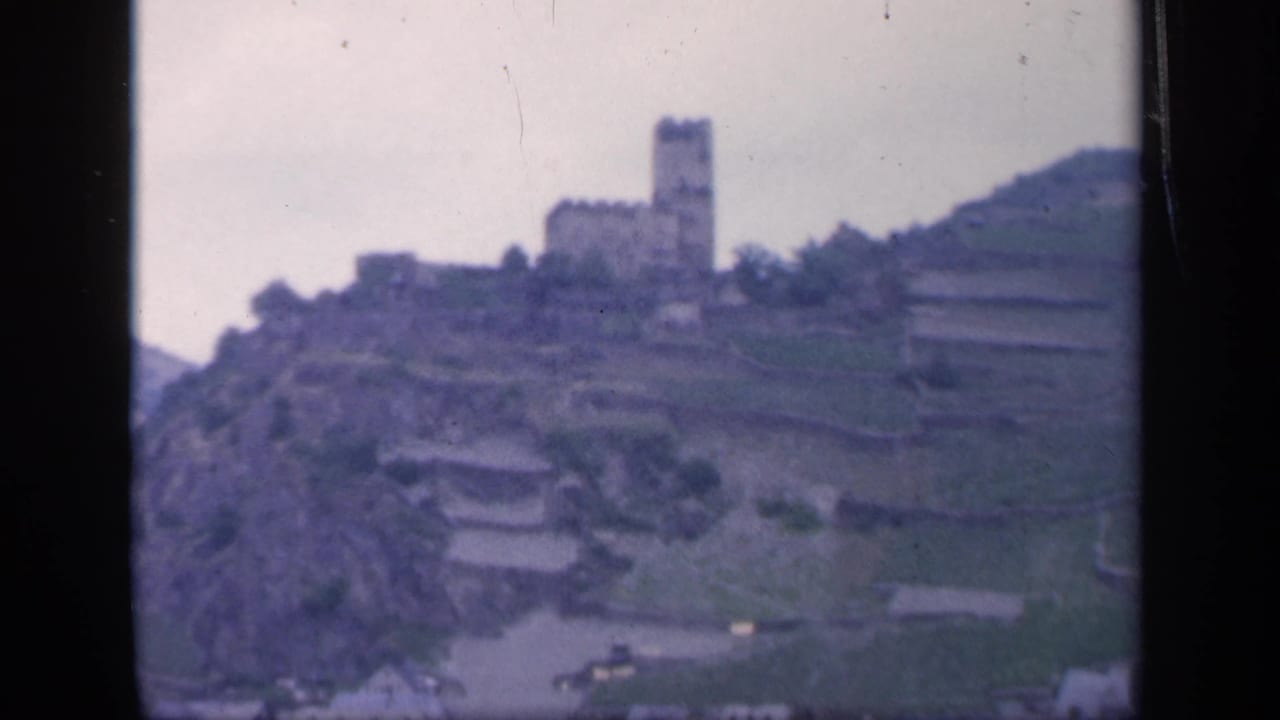 Castle and terraced hillside seen from across water or low ground.