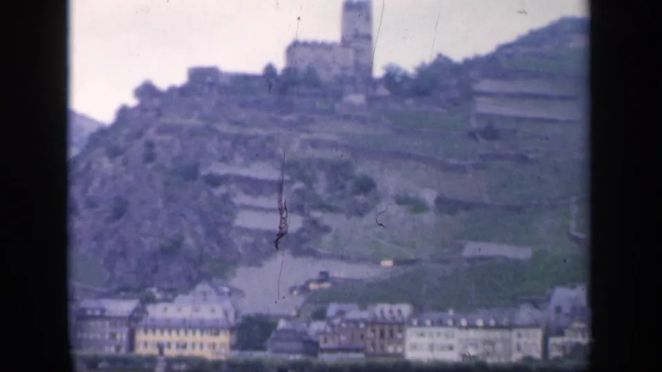 1949 Ireland home-movie frame showing the hilltop castle descending toward riverside buildings and water.
