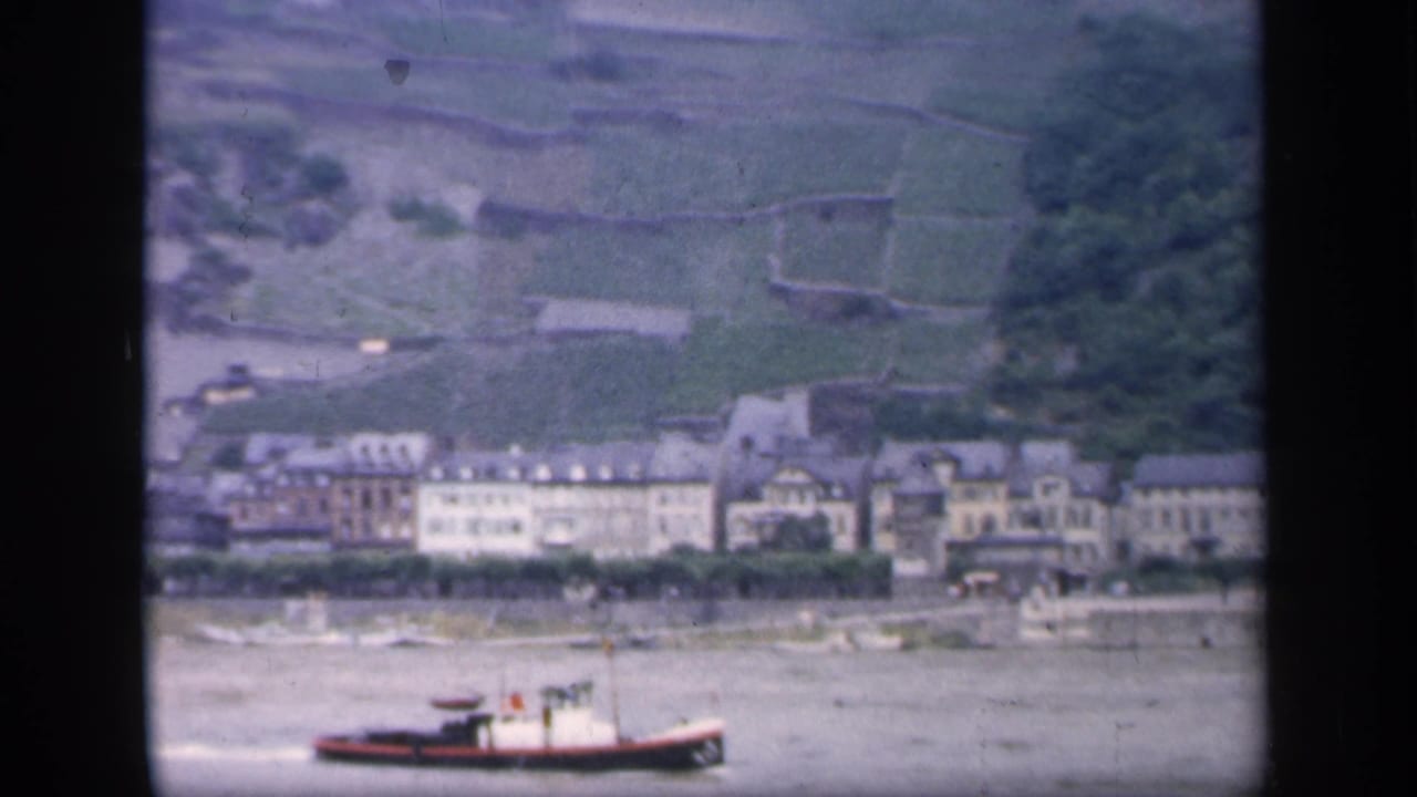 Boat near the riverfront with rows of buildings and hillside terraces beyond.