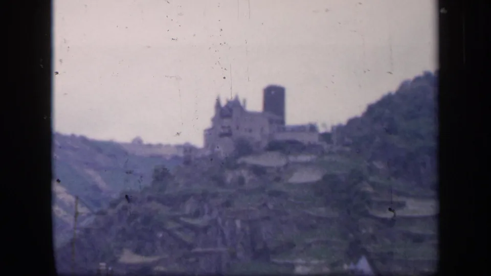 Soft 1949 Ireland home-movie view of a castle and tower above layered hillside terraces.