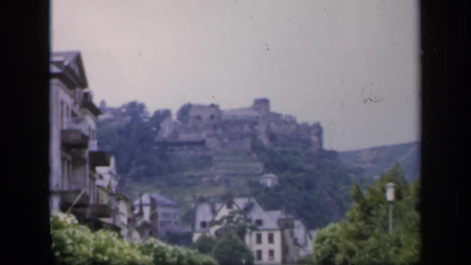 1949 Ireland frame showing a hilltop castle beyond town buildings, trees, and a valley slope.