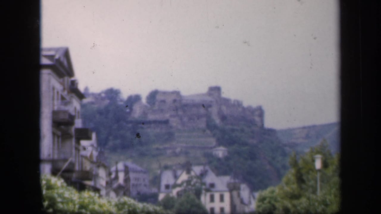 Soft 8mm frame of an Irish hilltop castle ruin overlooking town buildings and greenery in 1949.