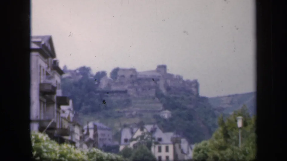 Soft 8mm frame of an Irish hilltop castle ruin overlooking town buildings and greenery in 1949.