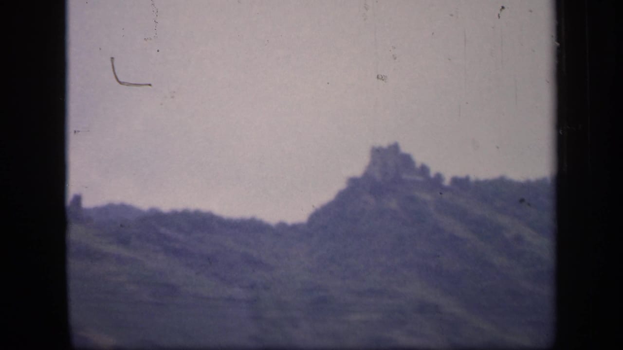 Hilltop ruin seen from farther right with dark film borders visible.