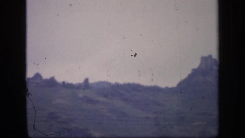 1949 Ireland home-movie frame of rolling hills and trees, with a castle-like ruin near the right edge.