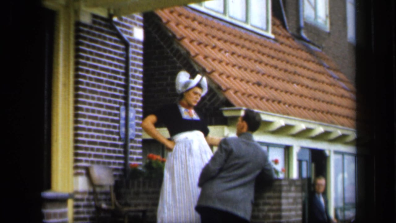 Woman on a doorstep looks toward a man in a gray suit approaching her.