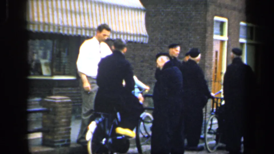 In the final 1949 Ireland frame, the group remains gathered with bicycles near brick building fronts while the younger man stands at the edge of the conversation.