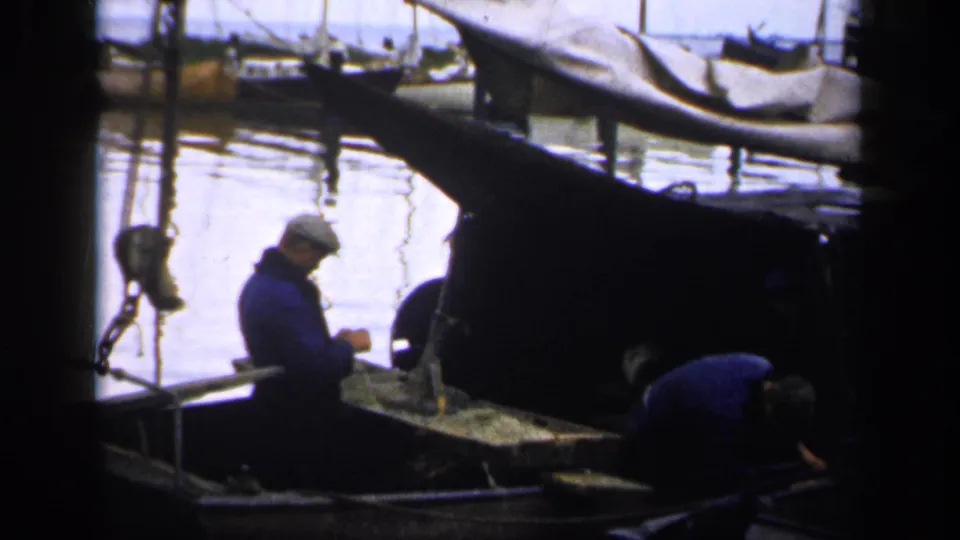 The small fishing boat scene continues, with a man in a cap standing near the center and another working low in the hull.