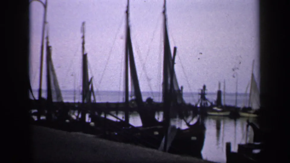 The final frame shows Irish dockside sailboats and masts in soft 8mm color, with people only faintly visible near the boats.