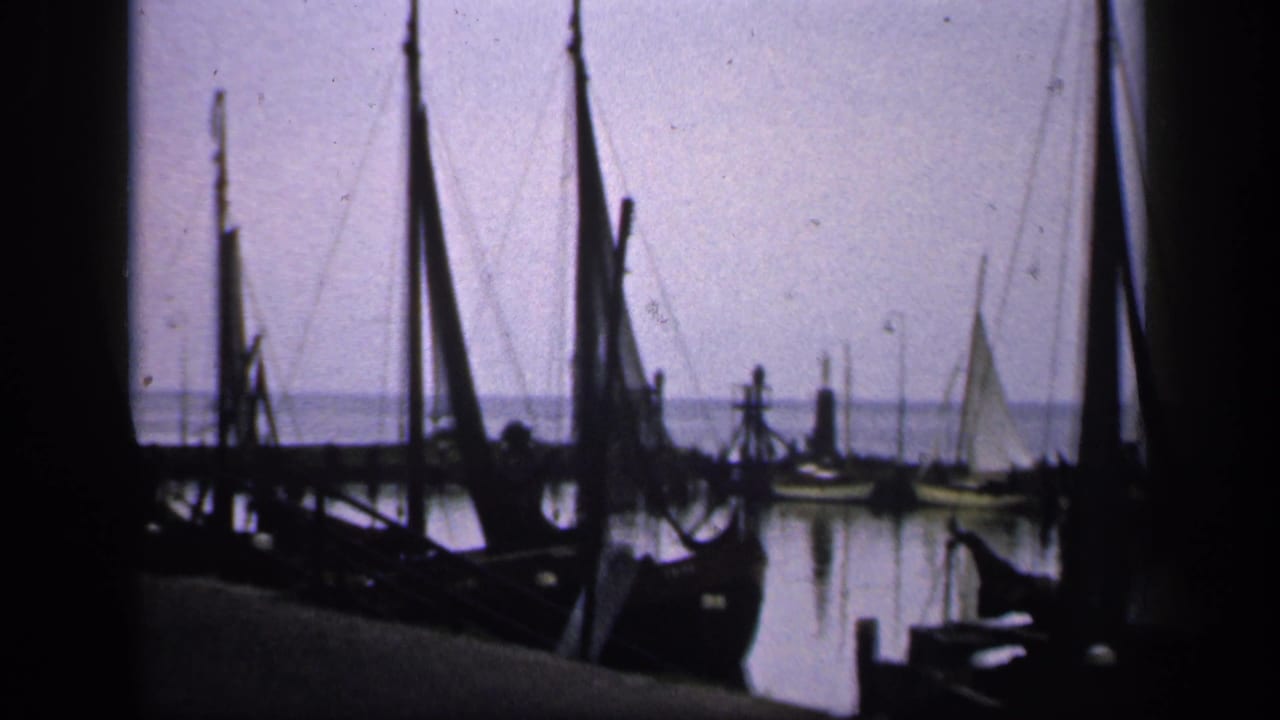 Moored sailboats and masts silhouetted across calm harbor water.
