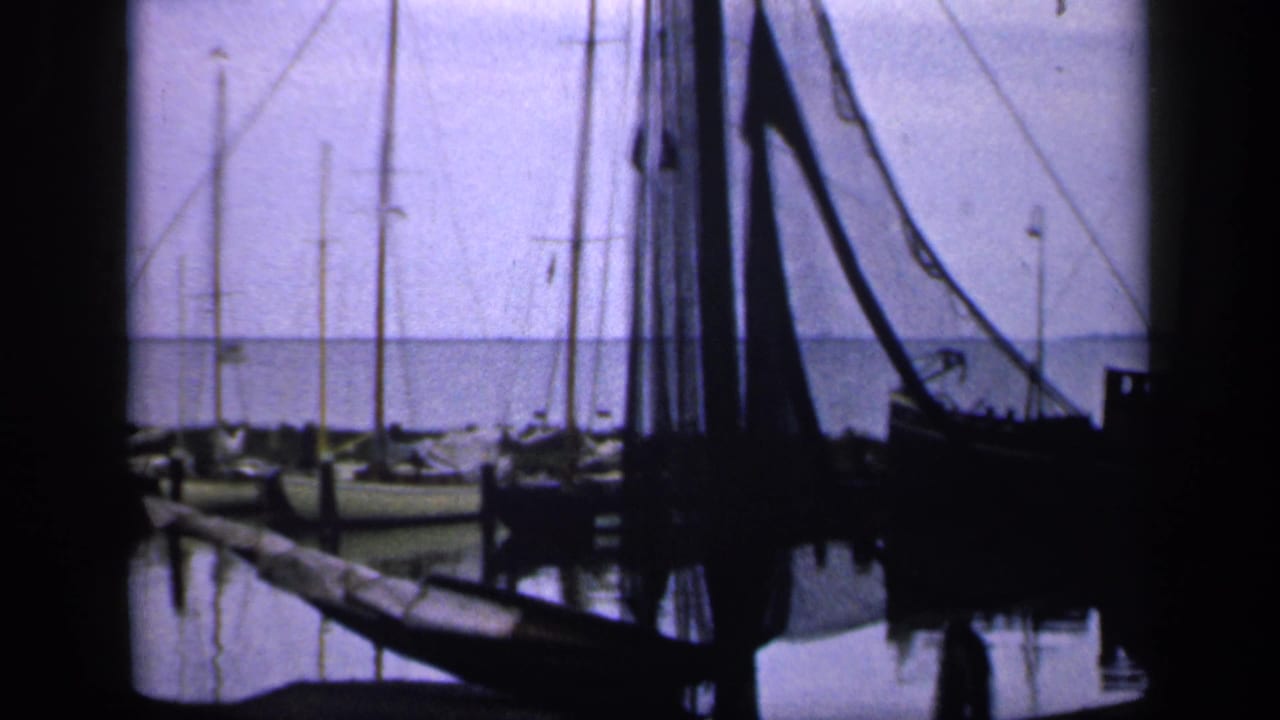 Moored fishing boats and masts silhouetted against pale water and sky.